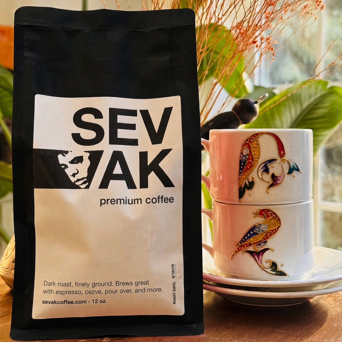 Black 12 oz bag of SEVAK No Spice pure dark roast beside two Armenian demitasse cups